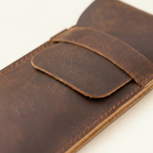 Close-up of a brown leather pen case flap with waxed saddle stitching