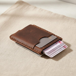 Coffee leather pop-up card holder with cards fanning out from the metal clip