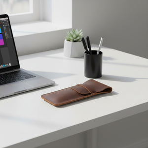 Brown leather pencil case on a desk with a laptop and office supplies