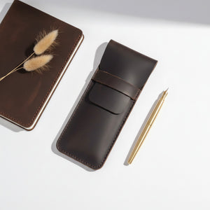 Coffee brown leather pen case with a gold pen and a journal