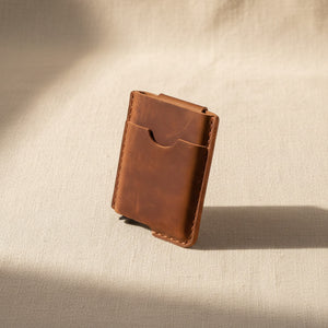 Slim brown leather card holder wallet standing upright on beige linen