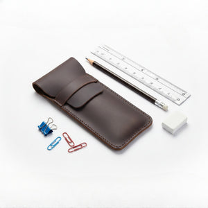 Brown leather pencil case with a pencil, ruler, eraser and paper clips