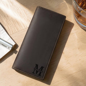 Personalized full grain leather long wallet with custom monogram engraving on a wood desk