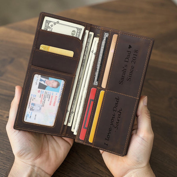 Hands holding open personalized leather long wallet showing custom inside engraving and card slots