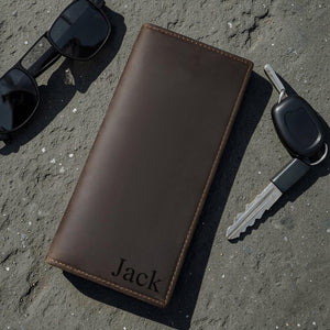 Engraved leather long wallet with custom monogram on a minimalist concrete surface