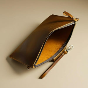 Brown leather clutch with open zipper showing interior