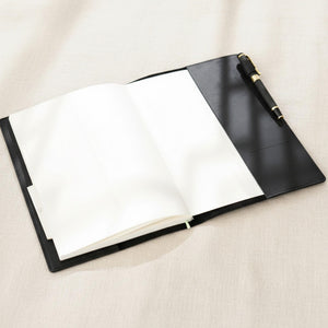 Open black leather journal cover with a pen on a light surface