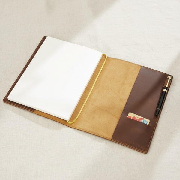 Open brown leather journal cover showing the card pocket, pen loop and refillable notebook