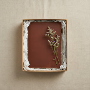 Brown leather journal cover with a bookmark in a gift box with dried flowers
