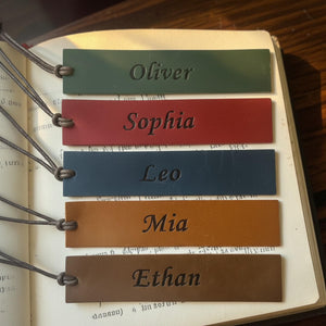 Engraved leather bookmarks stacked on hardcover books